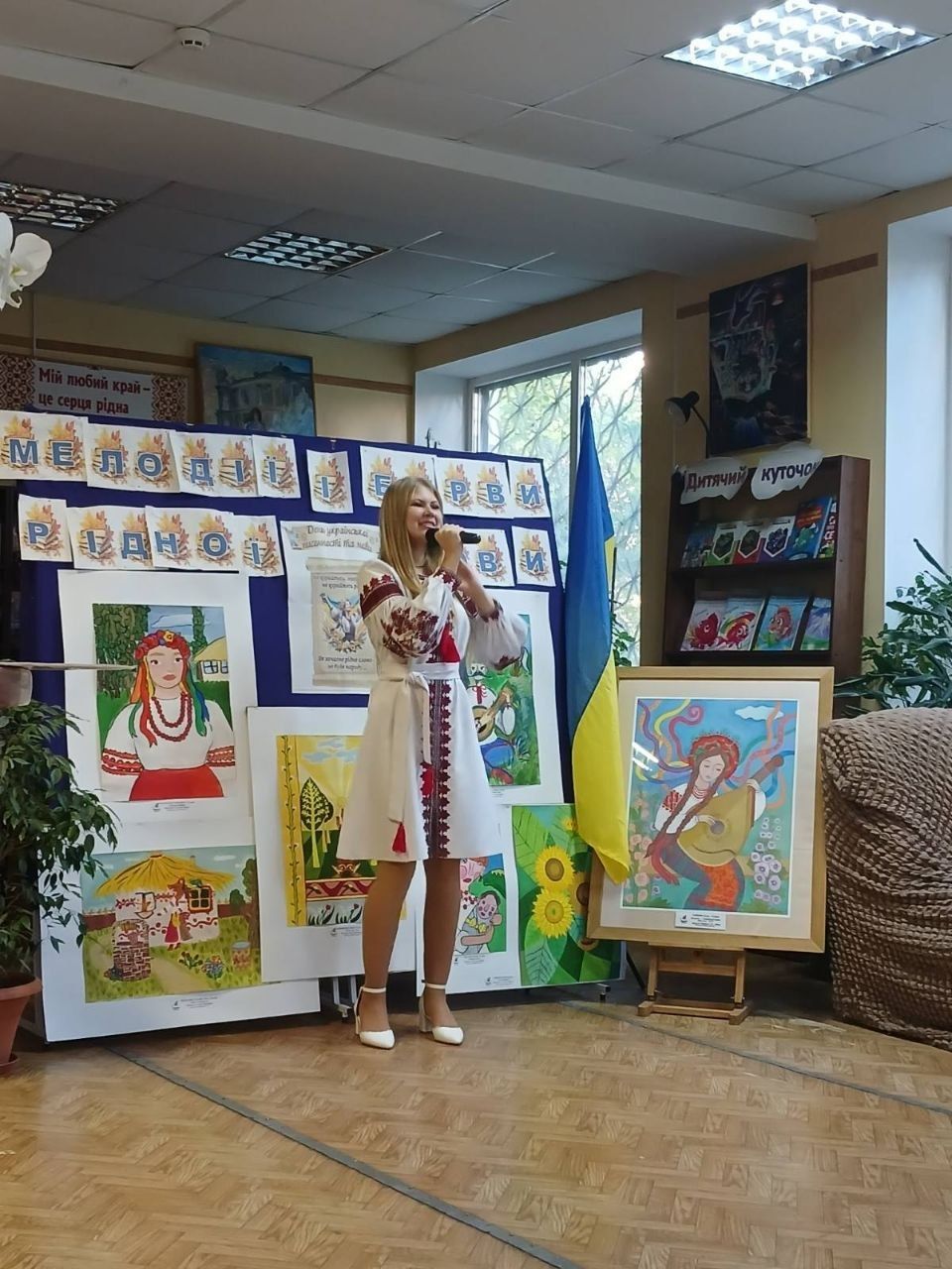 Виступ на імпрезі: співачка у вишиванці на тлі робіт учнів