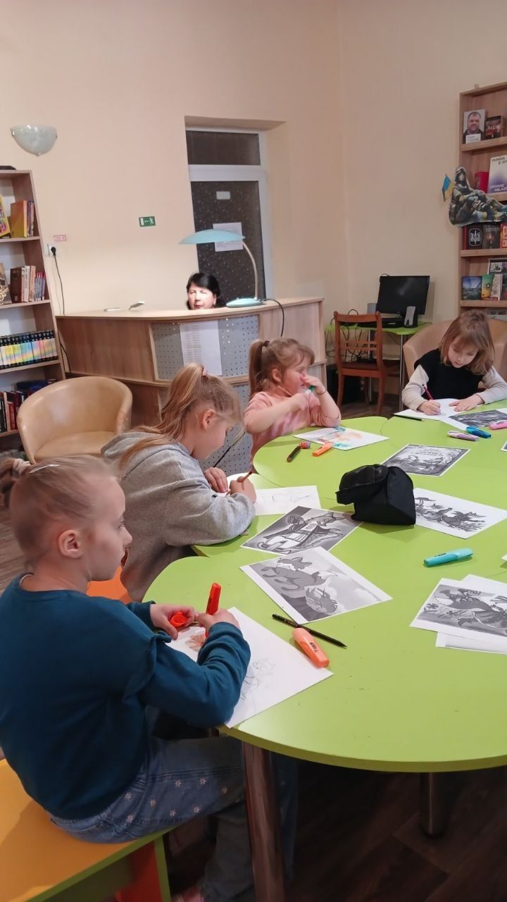 Діти малюють за столом у читальній залі бібліотеки