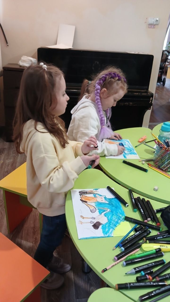 Дві дівчинки малюють маркерами на аркушах